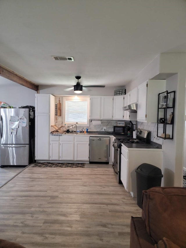 kitchen with sink, appliances with stainless steel finishes, tasteful backsplash, white cabinets, and light wood-type flooring