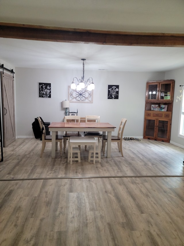 dining area with hardwood / wood-style flooring, a barn door, and a notable chandelier