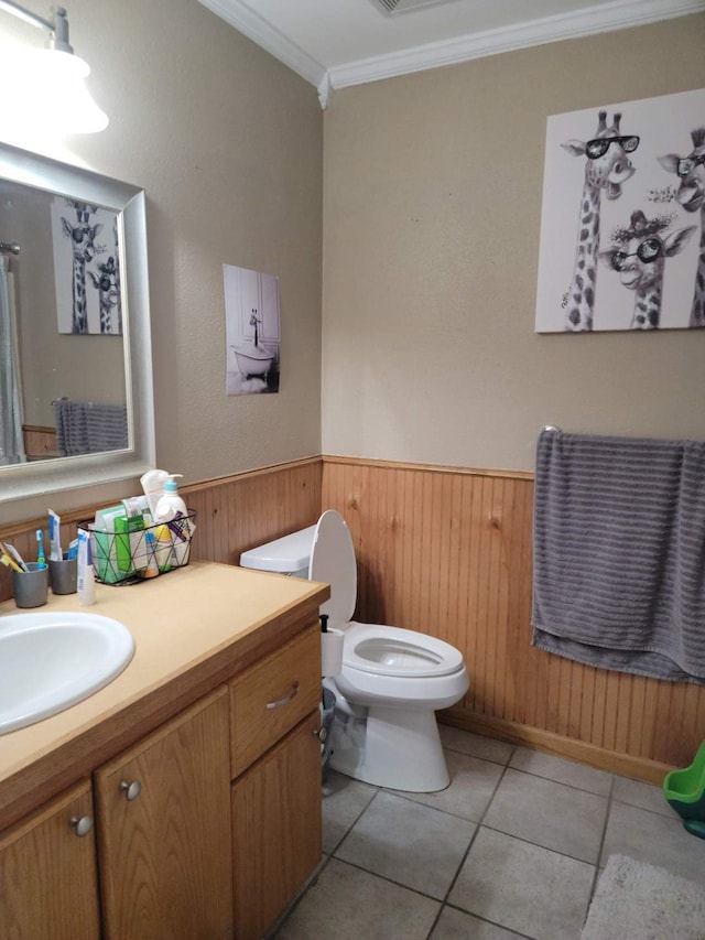 bathroom with crown molding, vanity, tile patterned floors, toilet, and wood walls