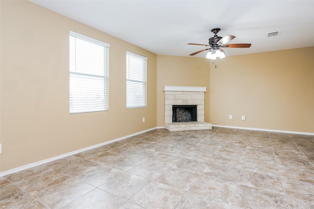 unfurnished living room featuring a stone fireplace and ceiling fan