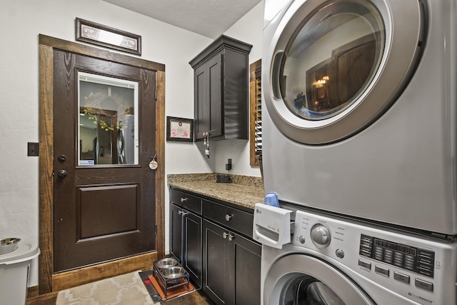 laundry room featuring cabinets and stacked washer and clothes dryer