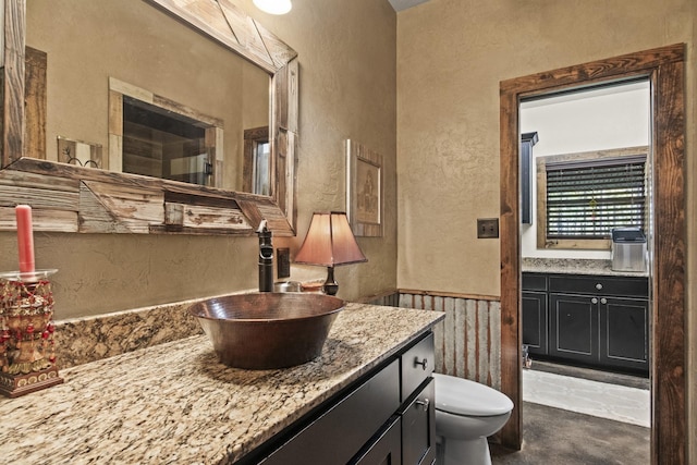 bathroom with vanity, concrete flooring, and toilet