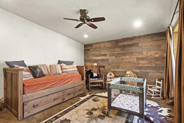 bedroom featuring ceiling fan and wood walls