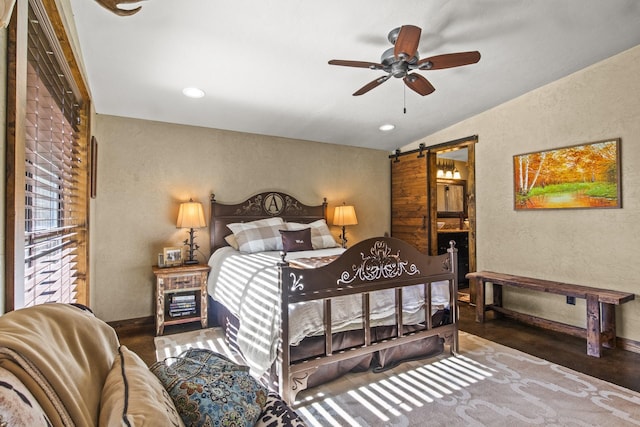 bedroom featuring ceiling fan, a barn door, vaulted ceiling, and carpet flooring