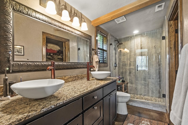 bathroom with beamed ceiling, vanity, toilet, and a shower with shower door