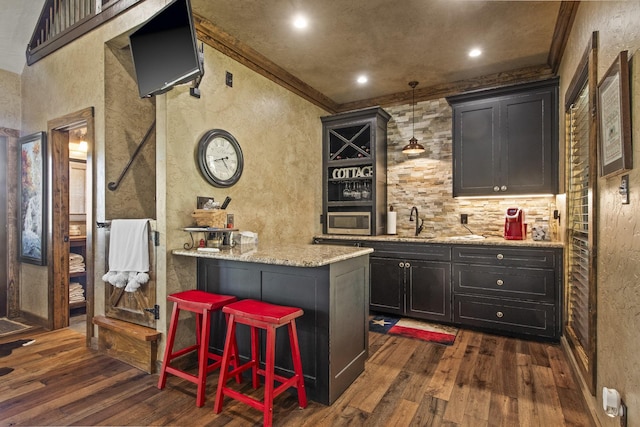 bar featuring pendant lighting, sink, dark hardwood / wood-style floors, ornamental molding, and light stone countertops