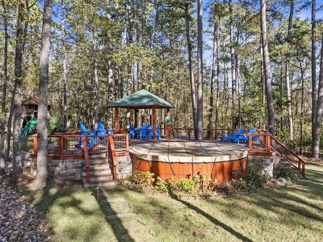 wooden deck with a hot tub and a lawn