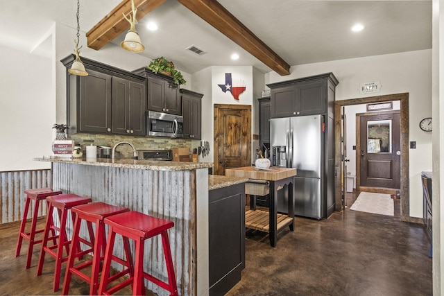 kitchen with a kitchen bar, appliances with stainless steel finishes, kitchen peninsula, beamed ceiling, and light stone countertops