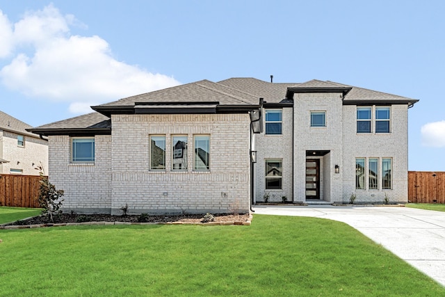 prairie-style home with brick siding, a front lawn, and fence