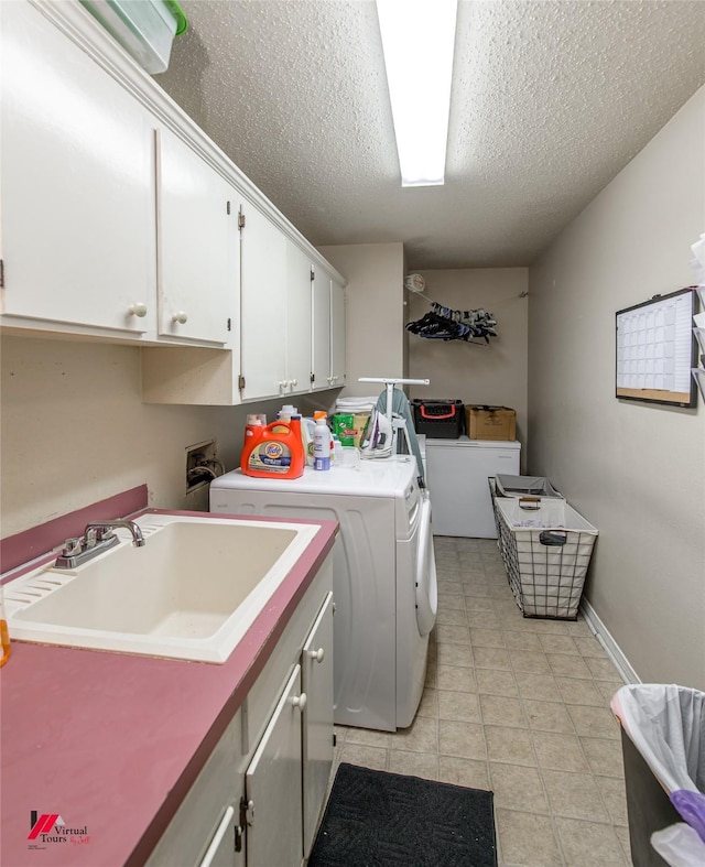 laundry room featuring cabinets, washing machine and dryer, sink, and a textured ceiling