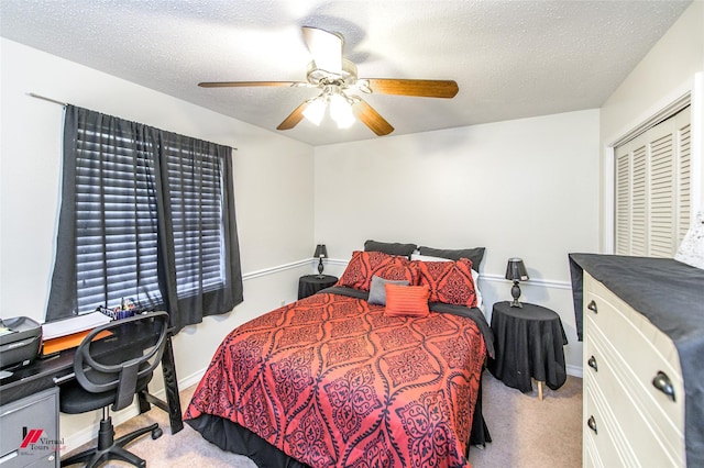 bedroom with a closet, ceiling fan, carpet floors, and a textured ceiling