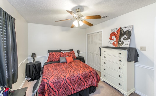 carpeted bedroom featuring ceiling fan, a textured ceiling, and a closet