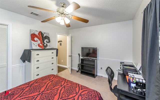 bedroom featuring ceiling fan, light carpet, and a textured ceiling