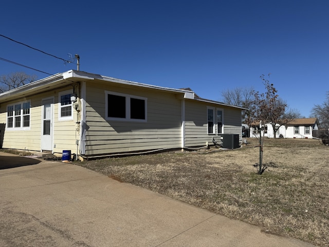 view of side of home with central AC unit and a lawn