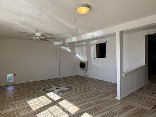 unfurnished room featuring hardwood / wood-style flooring, heating unit, and ceiling fan