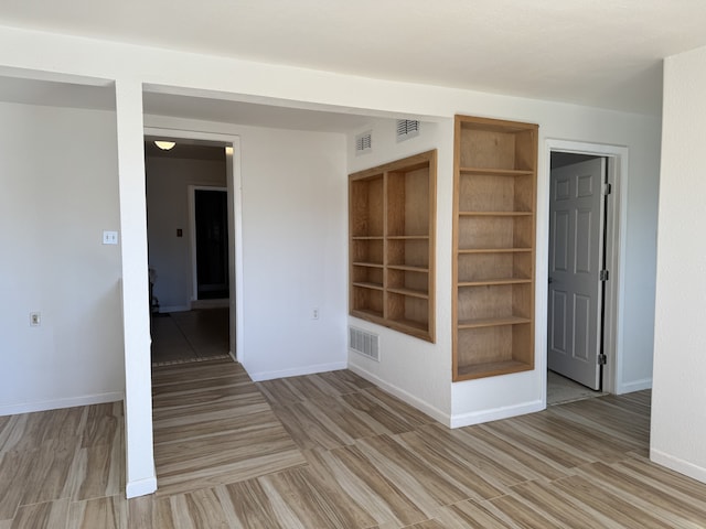 unfurnished room with built in features and light hardwood / wood-style floors