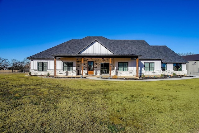 modern farmhouse style home with board and batten siding, a front lawn, covered porch, and stone siding