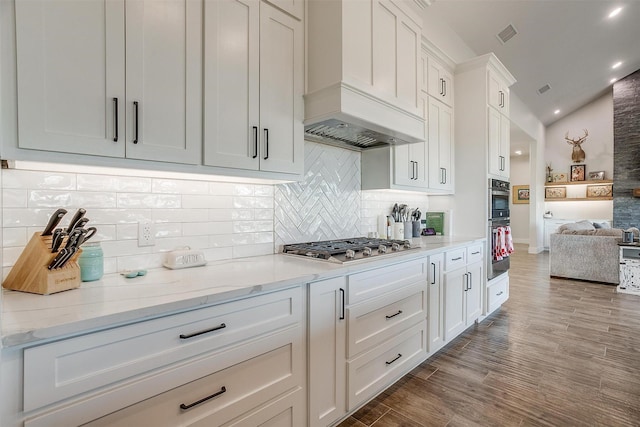 kitchen featuring premium range hood, white cabinetry, light stone counters, vaulted ceiling, and dark hardwood / wood-style floors