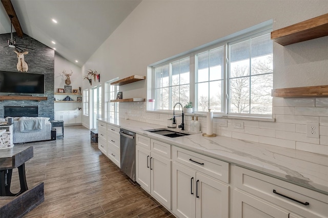 kitchen featuring tasteful backsplash, white cabinetry, sink, stainless steel dishwasher, and light stone counters