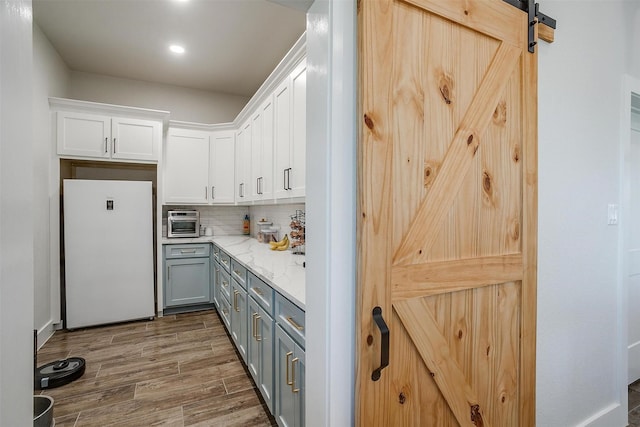 kitchen with a barn door, gray cabinets, white fridge, and white cabinets