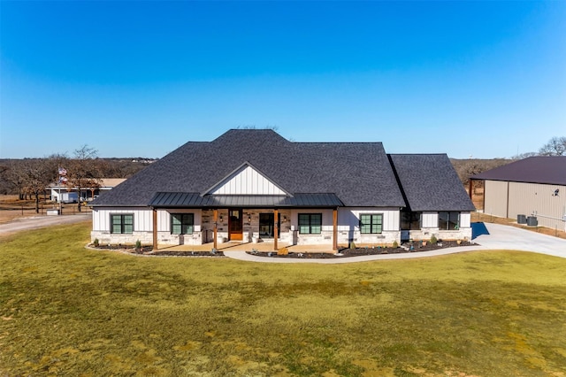 modern farmhouse style home with a standing seam roof, a porch, board and batten siding, and a front yard
