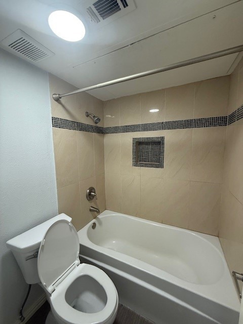 bathroom featuring tiled shower / bath combo and toilet