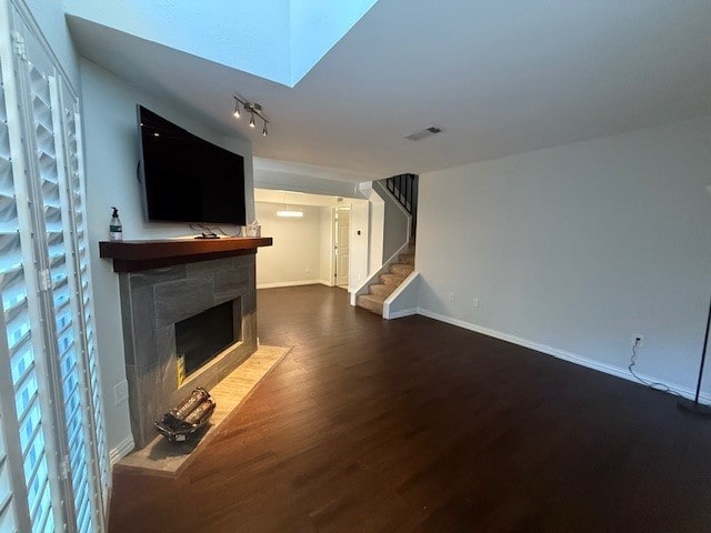 unfurnished living room featuring a tiled fireplace and dark hardwood / wood-style flooring