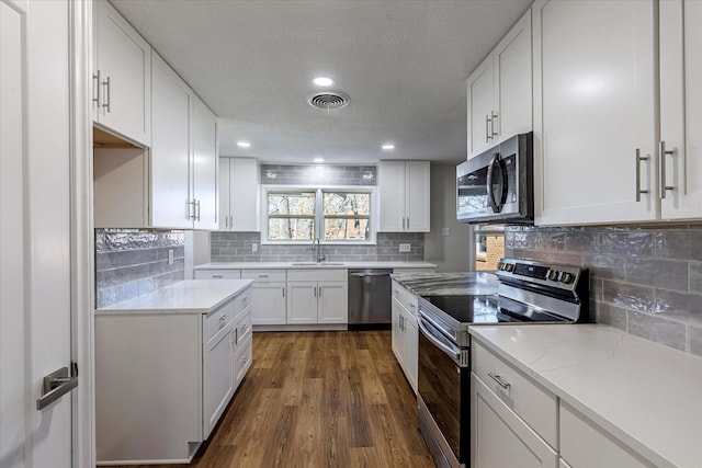 kitchen featuring sink, white cabinetry, stainless steel appliances, dark hardwood / wood-style floors, and tasteful backsplash