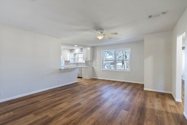 unfurnished living room featuring ceiling fan, dark hardwood / wood-style flooring, and sink