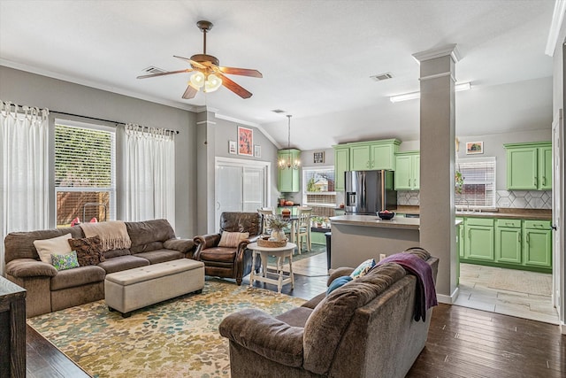 living room featuring dark wood-type flooring, lofted ceiling, sink, ornate columns, and ceiling fan with notable chandelier