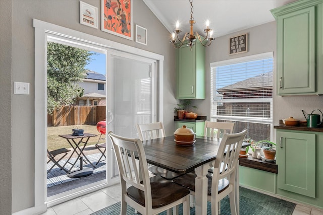 dining space with lofted ceiling, light tile patterned floors, and a notable chandelier