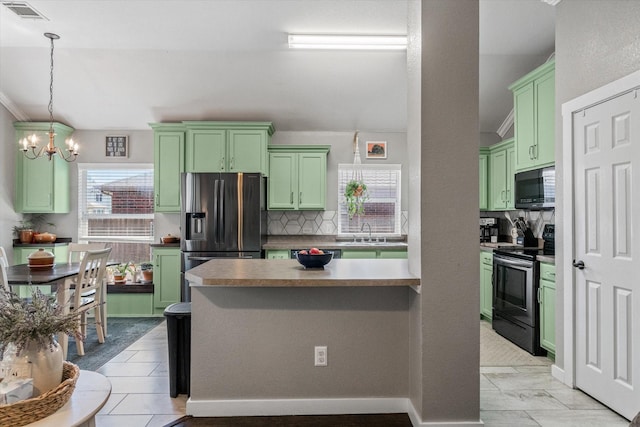 kitchen featuring tasteful backsplash, stainless steel appliances, a chandelier, and green cabinets