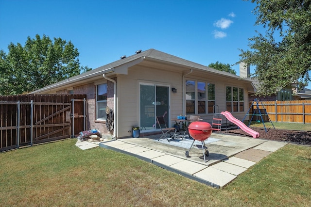 rear view of house with a playground, a patio, and a lawn