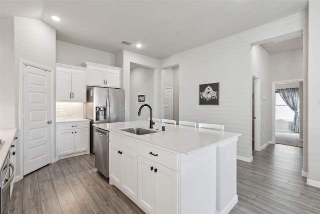 kitchen featuring sink, white cabinetry, appliances with stainless steel finishes, a kitchen island with sink, and light hardwood / wood-style floors