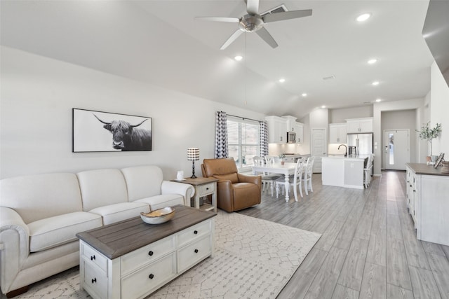 living room with vaulted ceiling, sink, ceiling fan, and light hardwood / wood-style flooring