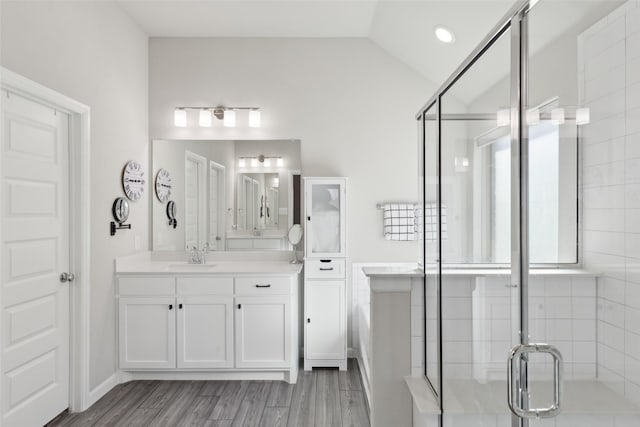 bathroom featuring vanity, a shower with shower door, and vaulted ceiling