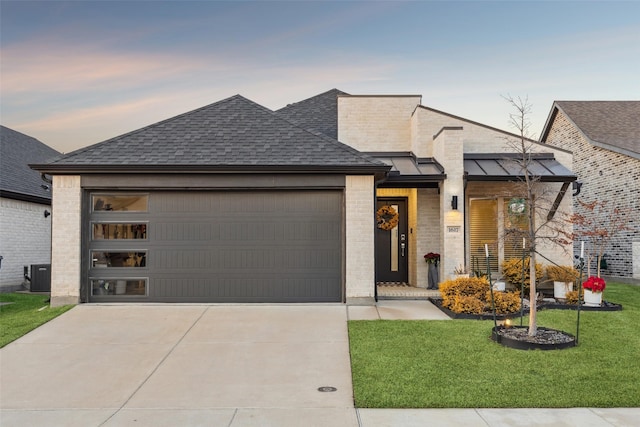 view of front of home featuring a garage, a lawn, and central air condition unit