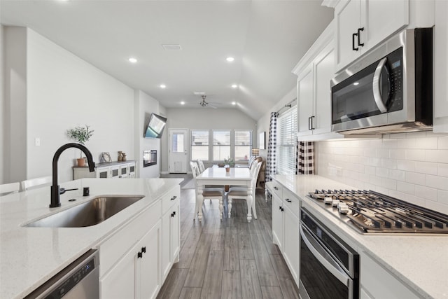 kitchen with dark hardwood / wood-style floors, white cabinetry, sink, backsplash, and stainless steel appliances