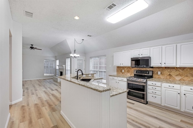 kitchen featuring lofted ceiling, double oven range, white cabinetry, and sink