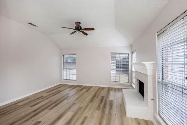 unfurnished living room featuring a brick fireplace, light hardwood / wood-style flooring, plenty of natural light, and vaulted ceiling