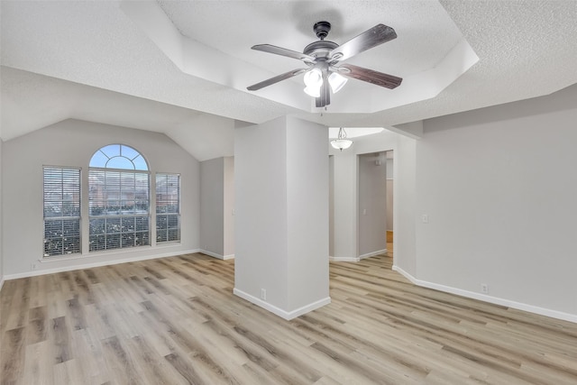 unfurnished living room featuring vaulted ceiling, ceiling fan, light hardwood / wood-style floors, and a textured ceiling