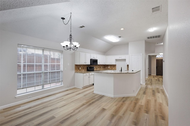 kitchen featuring decorative light fixtures, lofted ceiling, white cabinets, backsplash, and a textured ceiling