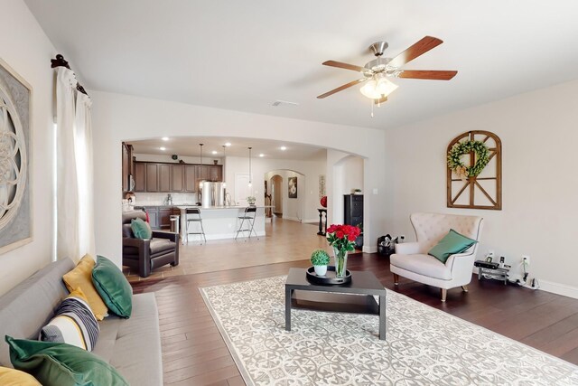 kitchen featuring sink, light stone counters, decorative light fixtures, stainless steel appliances, and a kitchen island with sink