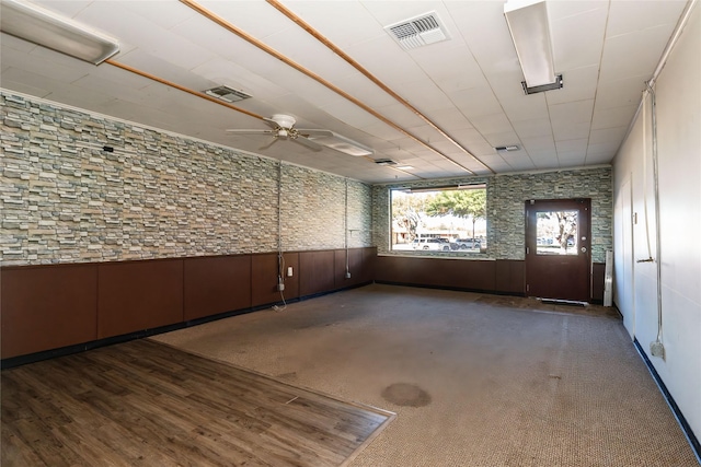 spare room featuring ceiling fan and wood walls