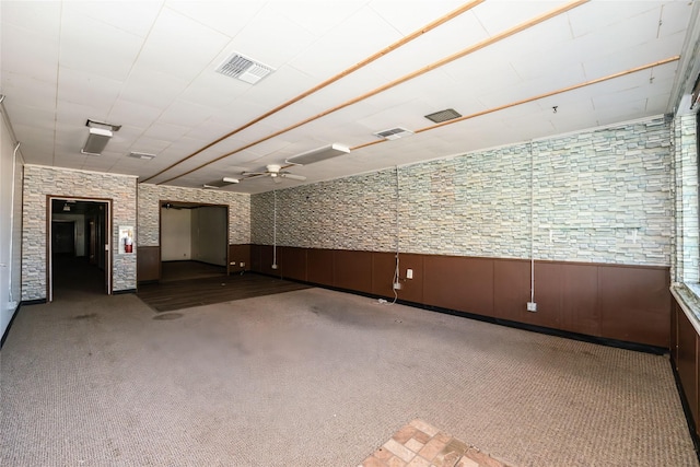 carpeted empty room featuring wooden walls