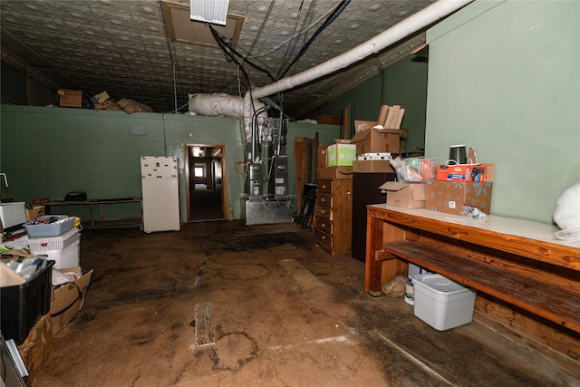 basement with white refrigerator and heating unit