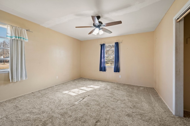 carpeted empty room with a wealth of natural light and ceiling fan