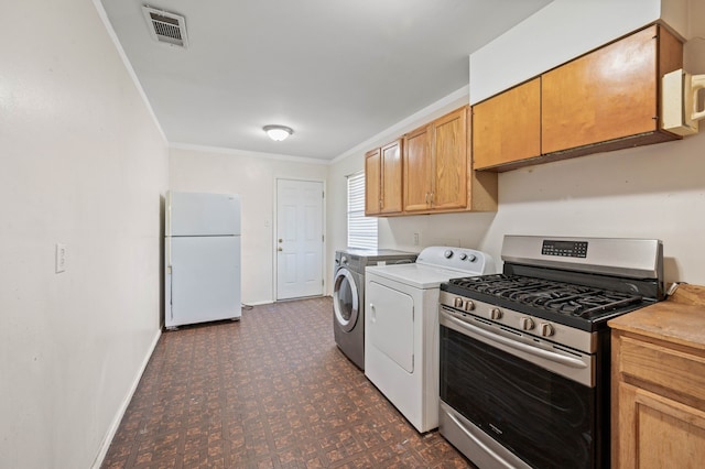 kitchen featuring washer and clothes dryer, stainless steel gas range, ornamental molding, and white fridge