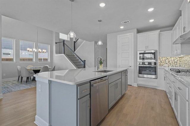 kitchen featuring sink, white cabinetry, a center island with sink, light wood-type flooring, and stainless steel appliances