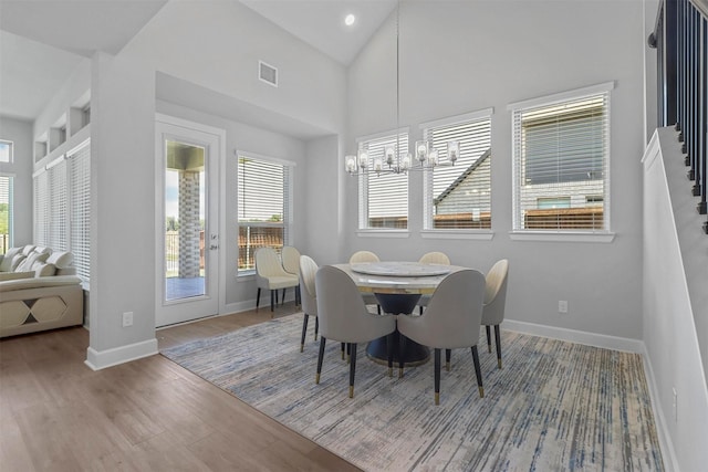 dining space with hardwood / wood-style flooring, a chandelier, and high vaulted ceiling